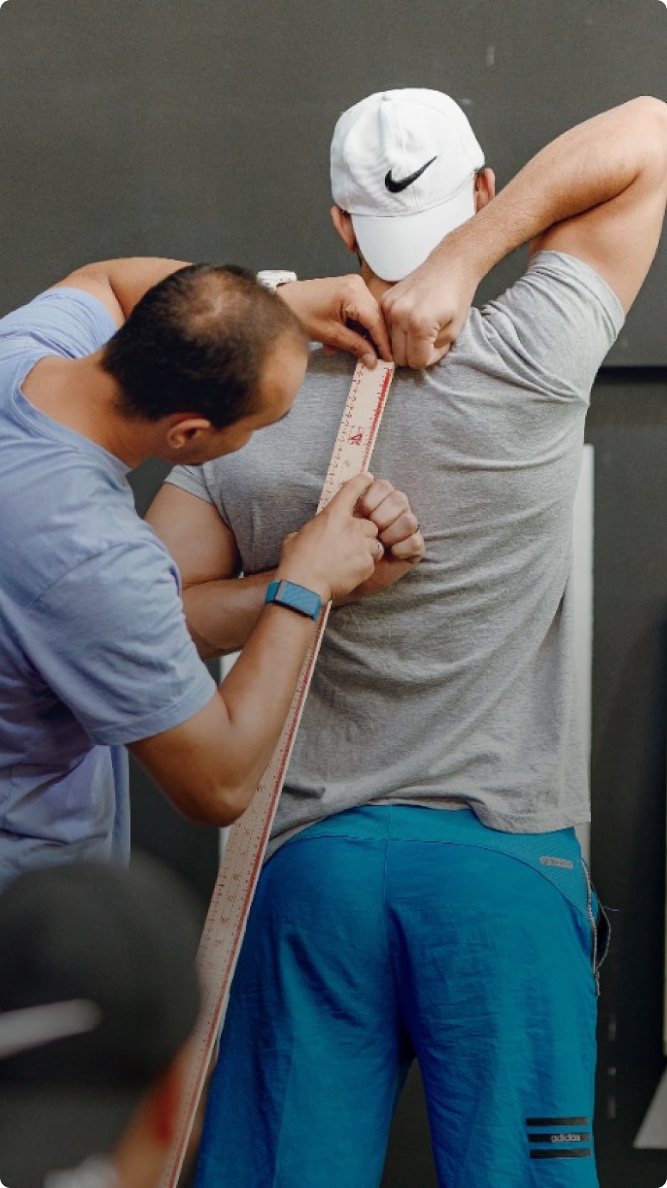 A coach measuring an athlete during a physical assessment.